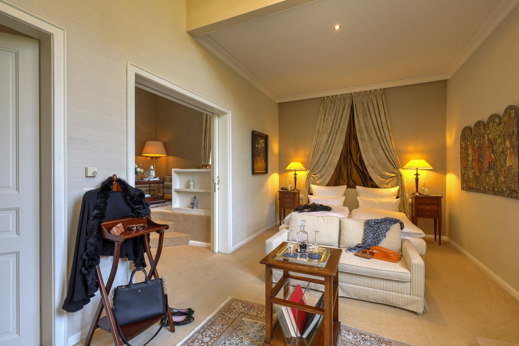 Der Schlafbereich in der Ustinov Suite im Schlosshotel Hugenpoet mit beigefarbener Einrichtung und luxuriösem Komfort.