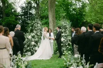 Ein Brautpaar vor einem Blumenbogen bei einer freien Trauung im Park im Schlosshotel Hugenpoet in Essen