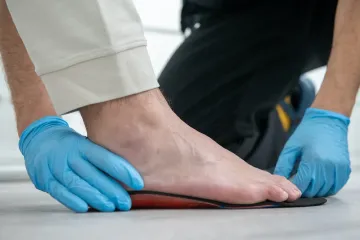 Manos enguantadas midiendo un pie descalzo en una báscula o dispositivo para medir el pie.