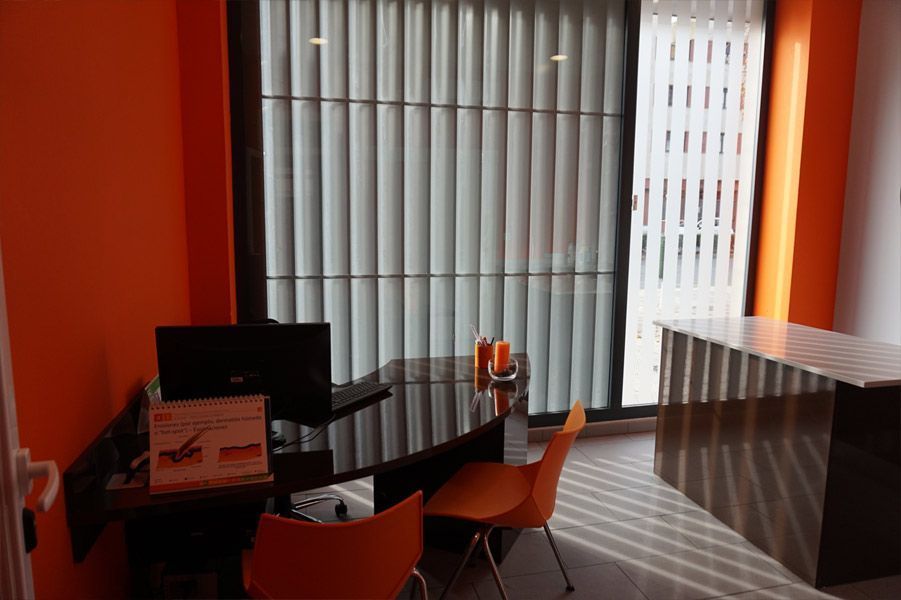 Un escritorio con una computadora portátil encima en una habitación con paredes naranjas.