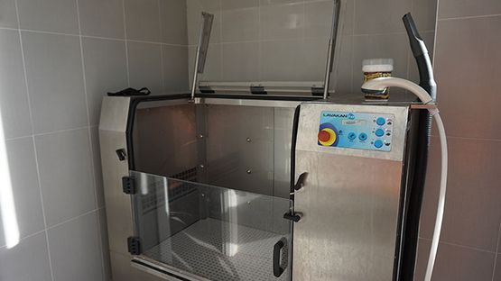 Una máquina de acero inoxidable con una manguera conectada a ella está colocada en una habitación.