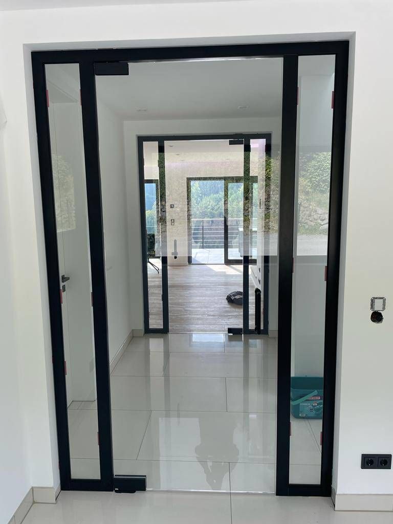 ein Flur mit Glastüren und einer schwarzen Tür .