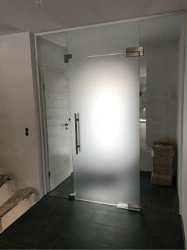 eine Glastür in einem Raum mit einer Tür dahinter .