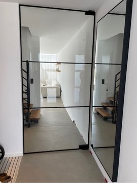 ein Flur mit einer Glastür und einem Spiegel .