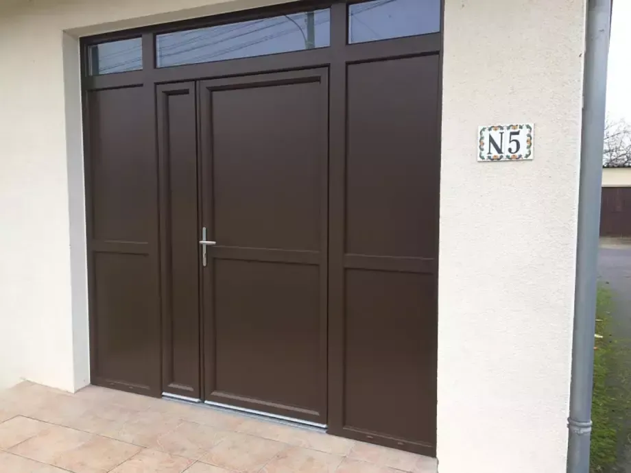 Porte d’entrée blanche à côté d’une porte moustiquaire grise et d’une fenêtre encadrée de bois, sur la façade d’un bâtiment.