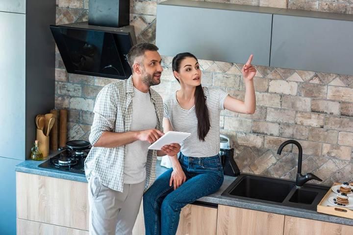 Deux personnes dans une cuisine moderne discutent d’une recette en regardant un smartphone