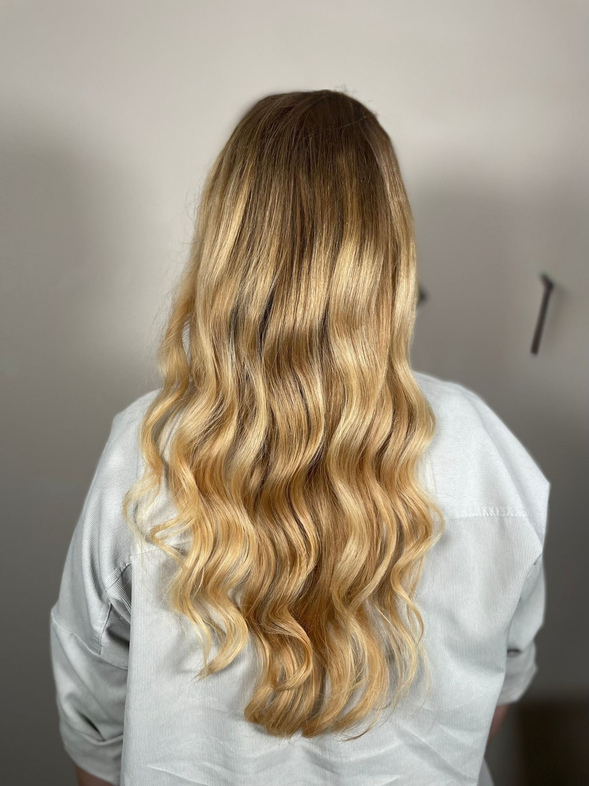 A woman with long blonde hair is wearing a white shirt.