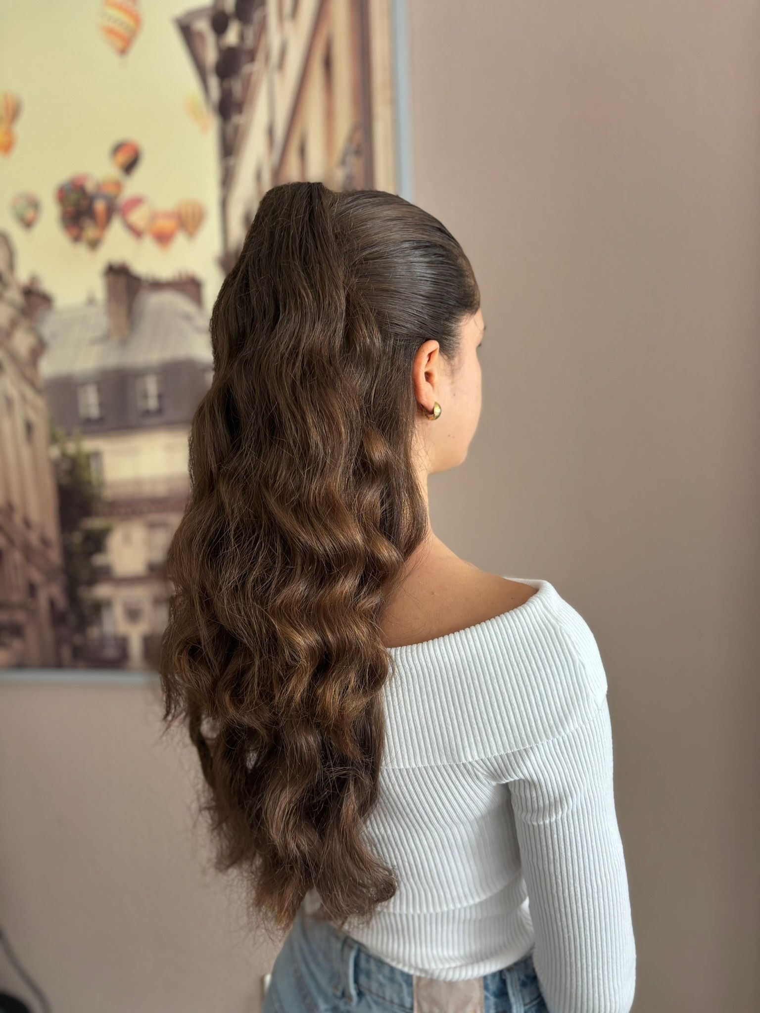 A woman with long hair is wearing a white sweater and jeans.