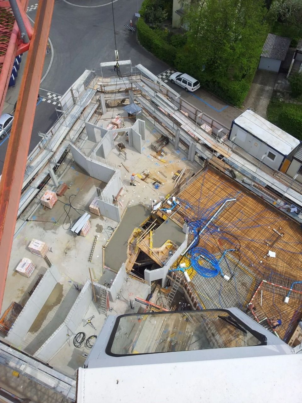 Draufsicht auf eine Baustelle mit Betonwänden, einem mit Stahlbeton bedeckten Boden und Arbeitern am Boden.