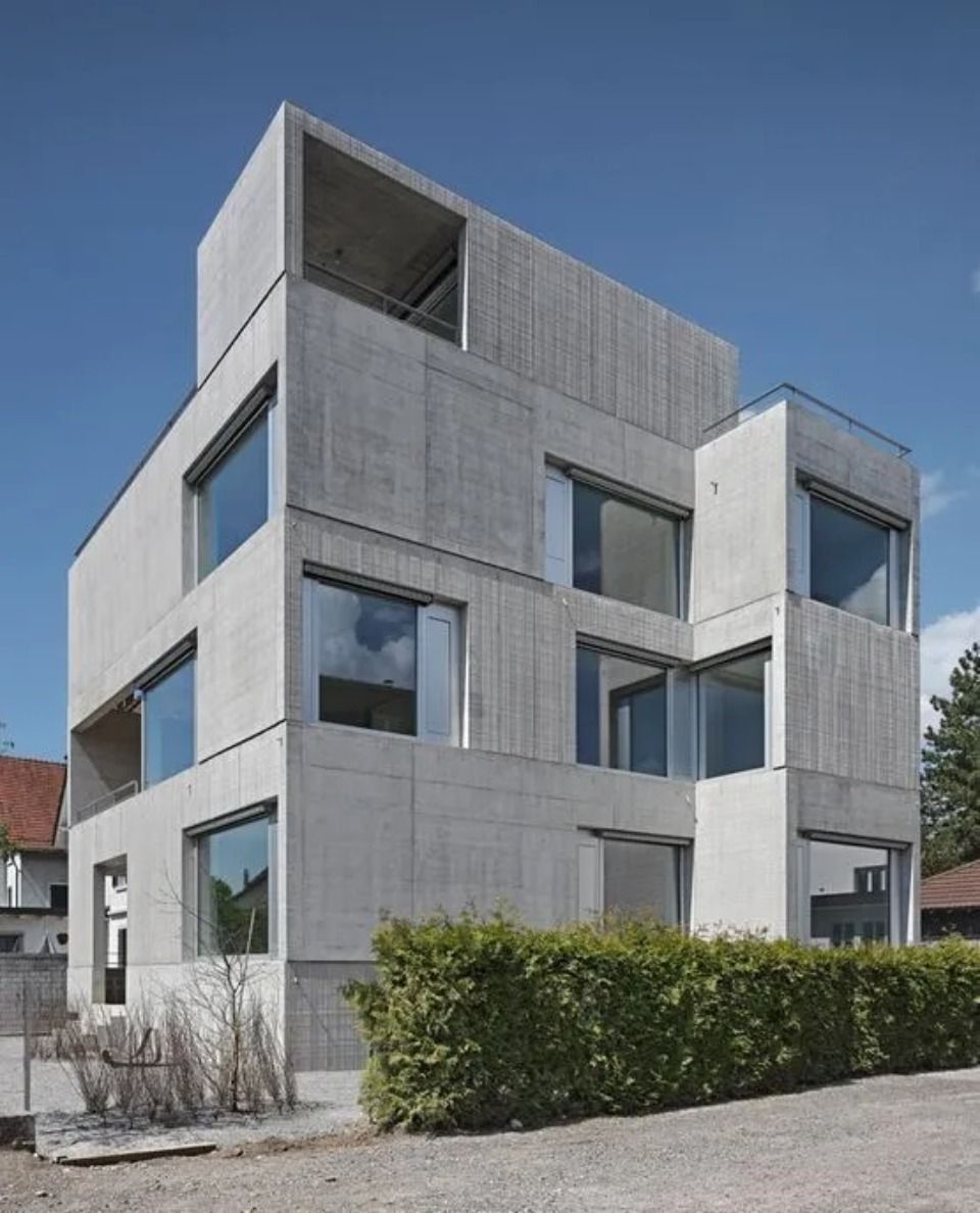 Ein mehrstöckiges, brutalistisches Wohngebäude aus Beton mit blockartiger, geschichteter Gestaltung und grossen quadratischen Fenstern.