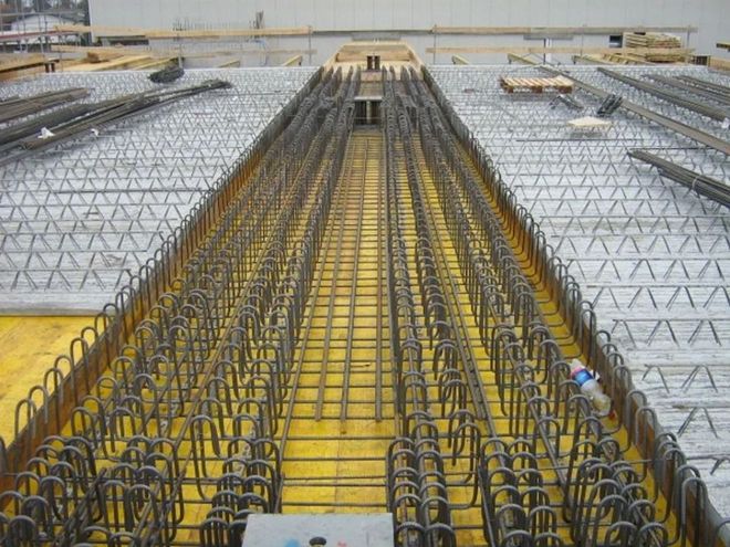 Baustelle mit Stahlbewehrung für einen Betonbodenbalken zwischen Metalldeckplatten.