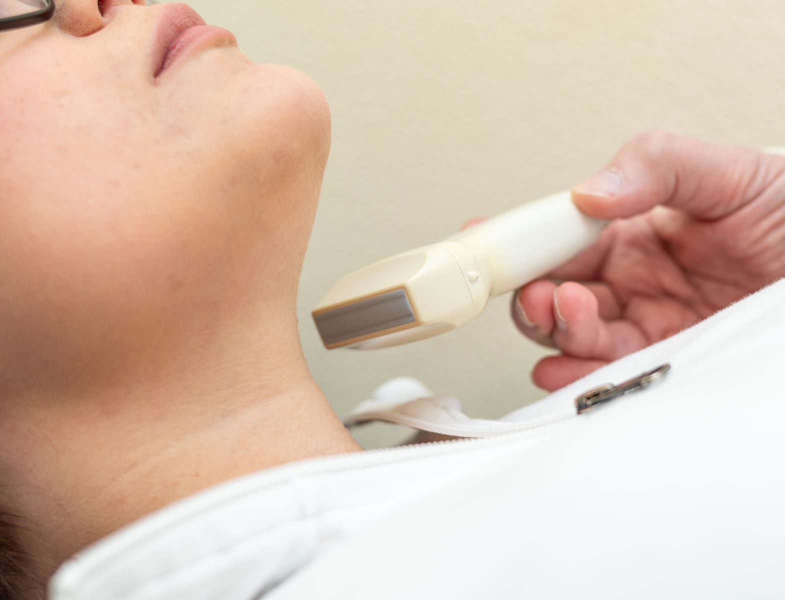 Bei einer Frau wird eine Ultraschalluntersuchung des Halses durchgeführt.