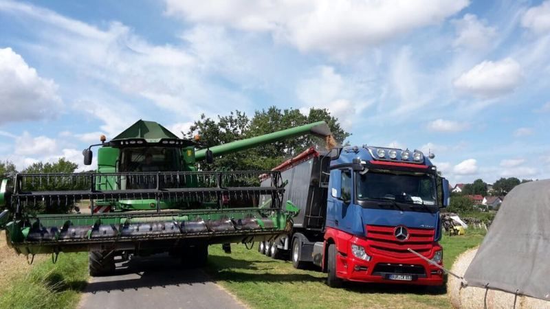 Mähdrescher belädt einen LKW mit Futtermittel frisch vom Feld