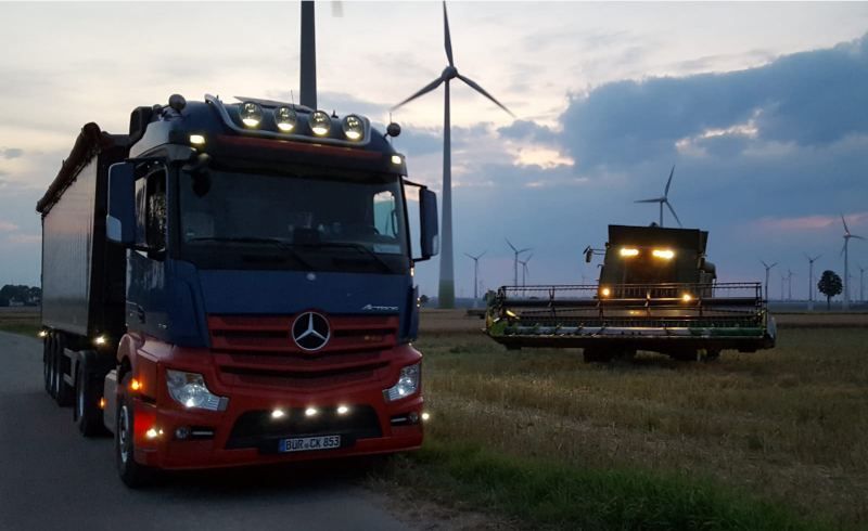 LKW und Mähdrescher in der Dämmerung am Feld