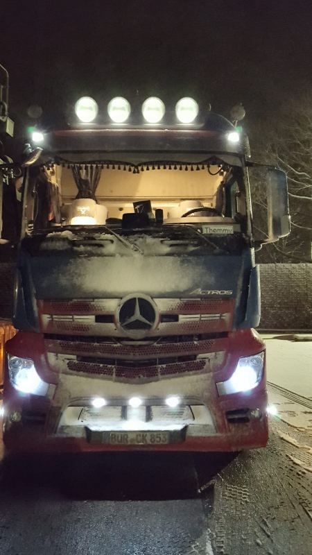 LKW in der Dunkelheit bei Schnee mit eingeschalteter Lichtanlage