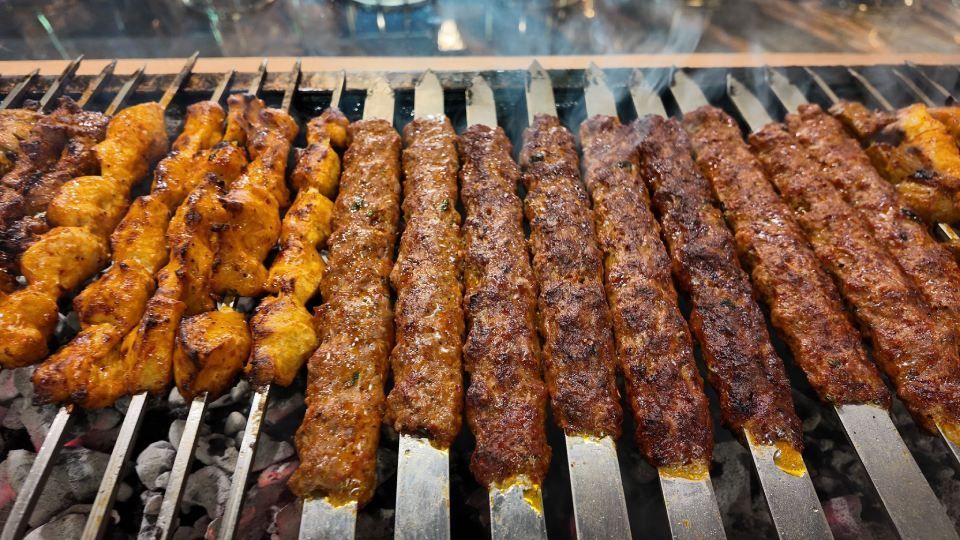 Gegrillte Spiesse mit mariniertem Fleisch und Hähnchen brutzeln über offener Holzkohle.