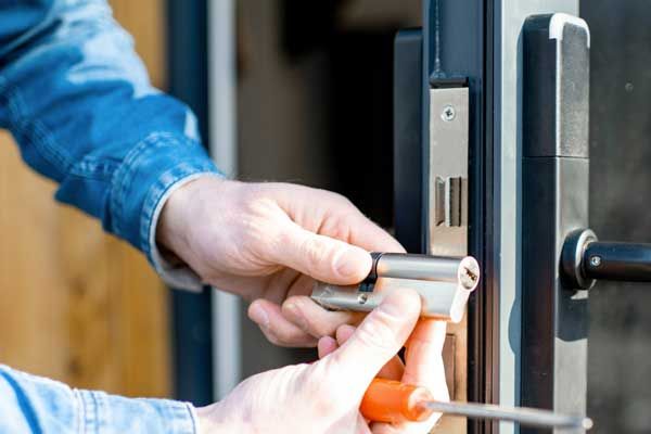 Un hombre está arreglando una cerradura de puerta con un destornillador.