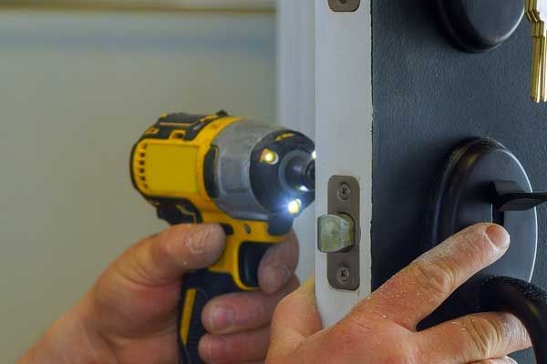 Una persona está usando un taladro para arreglar una cerradura de puerta.