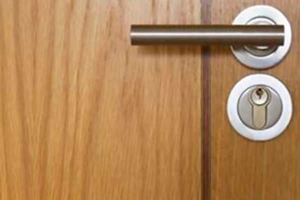 Un primer plano de una manija de puerta en una puerta de madera.