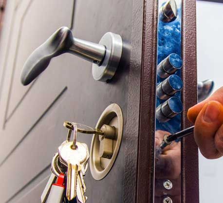Una persona está arreglando una cerradura de puerta con un destornillador.