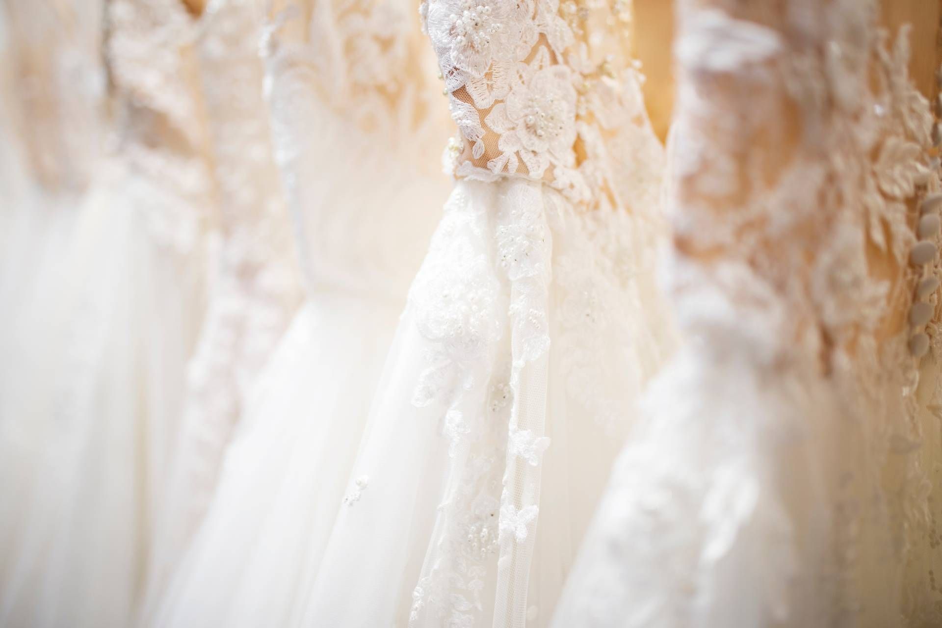 Eine Reihe von Brautkleidern hängt an einer Stange in einem Geschäft