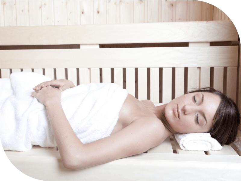Femme allongée dans l'espace sauna avec serviette blanche