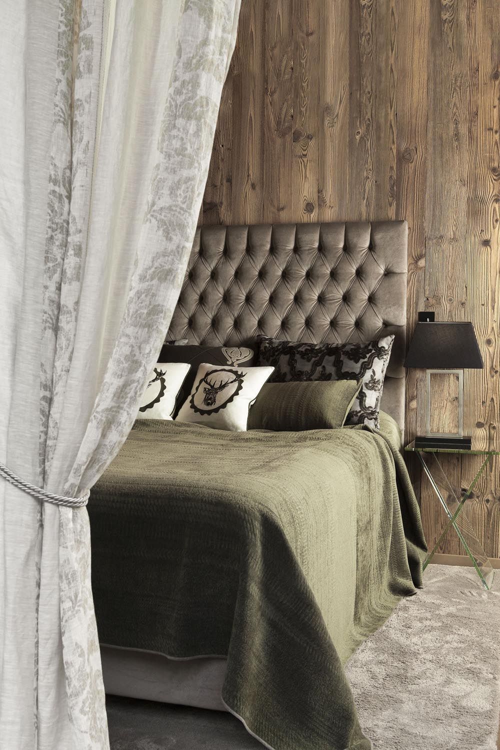 Ein Schlafzimmer mit Bett, Vorhängen und einer Holzwand.