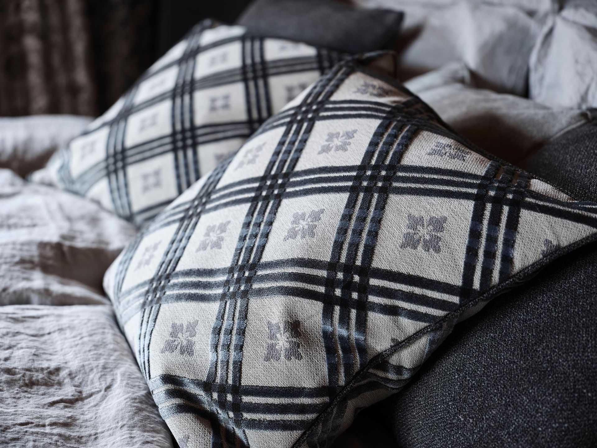 Auf einem Bett liegen zwei karierte Kissen.