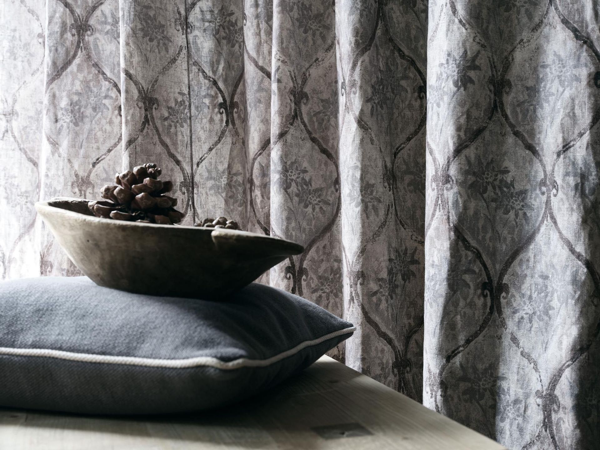 Eine Schale mit Tannenzapfen steht auf einem Kissen auf einem Tisch