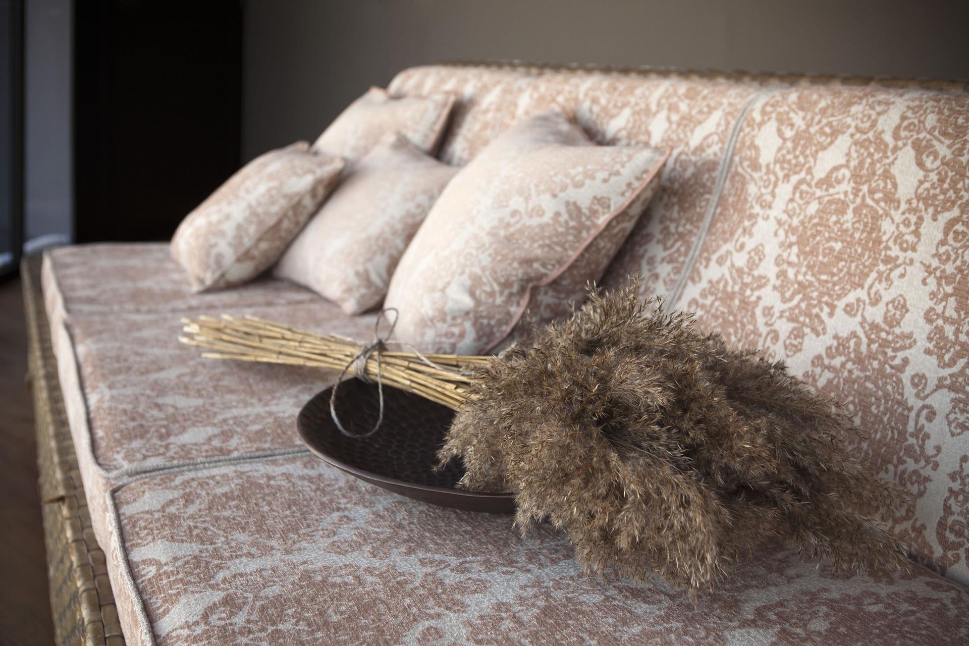 Eine Couch mit Kissen und einer Vase mit getrocknetem Gras darauf.