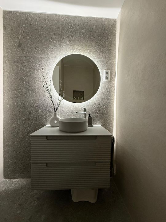 Un baño con lavabo y espejo redondo.