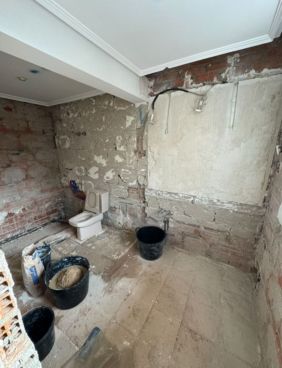 Un baño en construcción con un inodoro y cubos en el suelo.