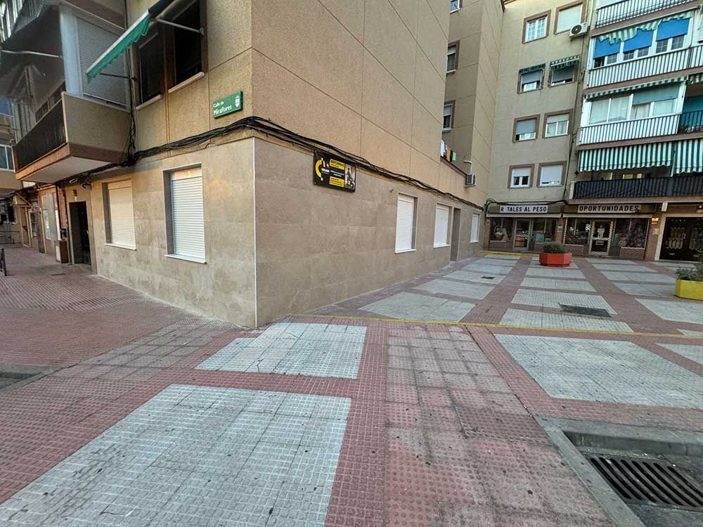 Acera urbana junto a edificios de apartamentos de color beige con adoquines de colores rojo y gris con dibujos.