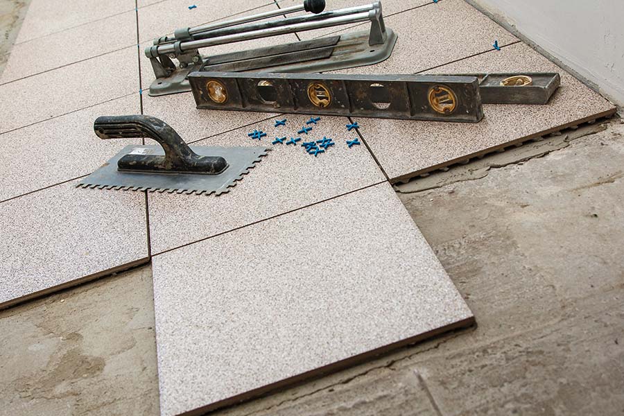 Des outils sont posés sur du carrelage en cours de pose