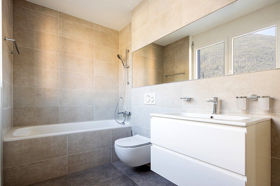 Salle de bains entièrement carrelée comprenant une baignoire, un cabinet et un lavabo