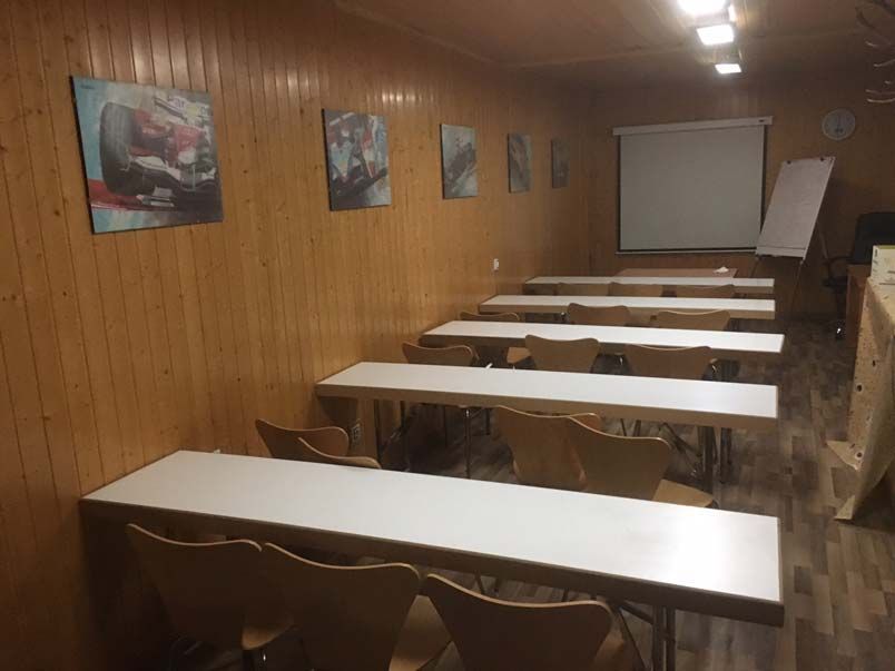 Un aula con mesas y sillas y una pantalla de proyección.