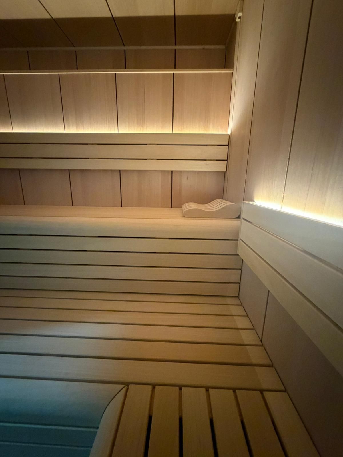 Intérieur de sauna en bois à l'éclairage chaleureux, avec bancs et murs à lattes.