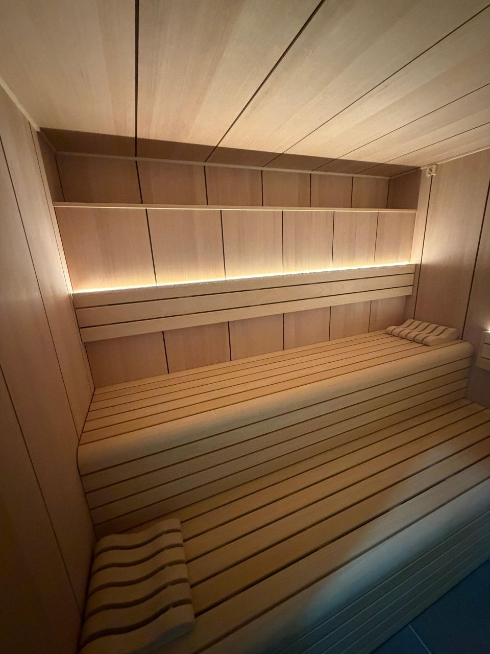 Sauna lambrissé avec banquettes et éclairage d'ambiance chaleureux