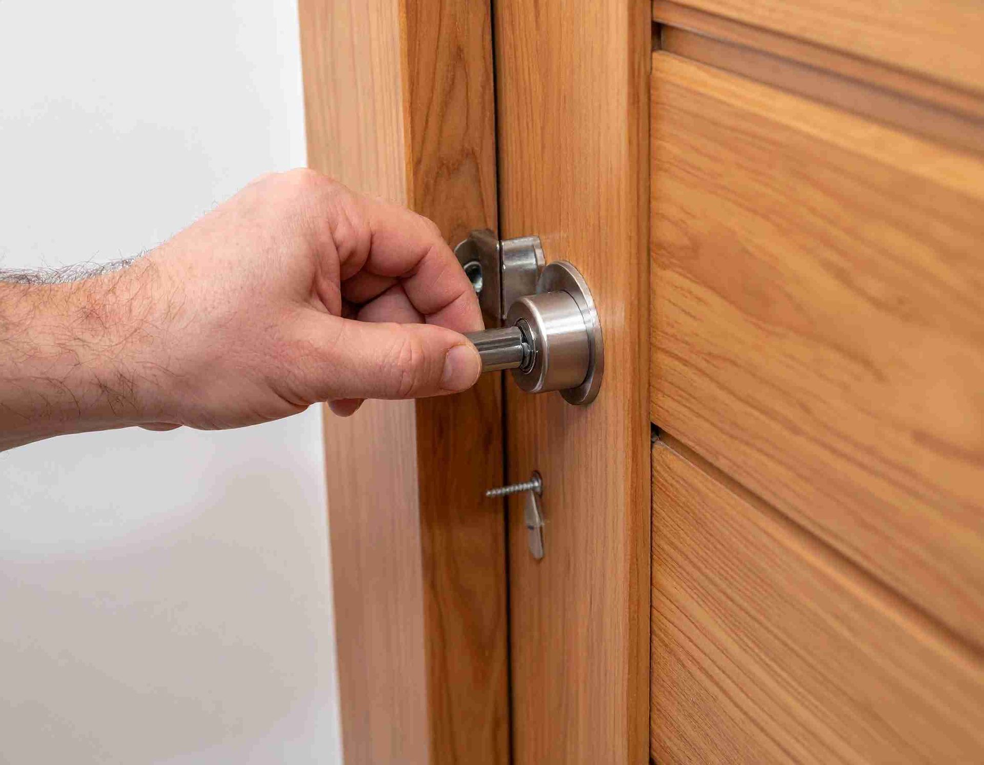 Mano girando una llave en la cerradura de una puerta de madera, en el interior.