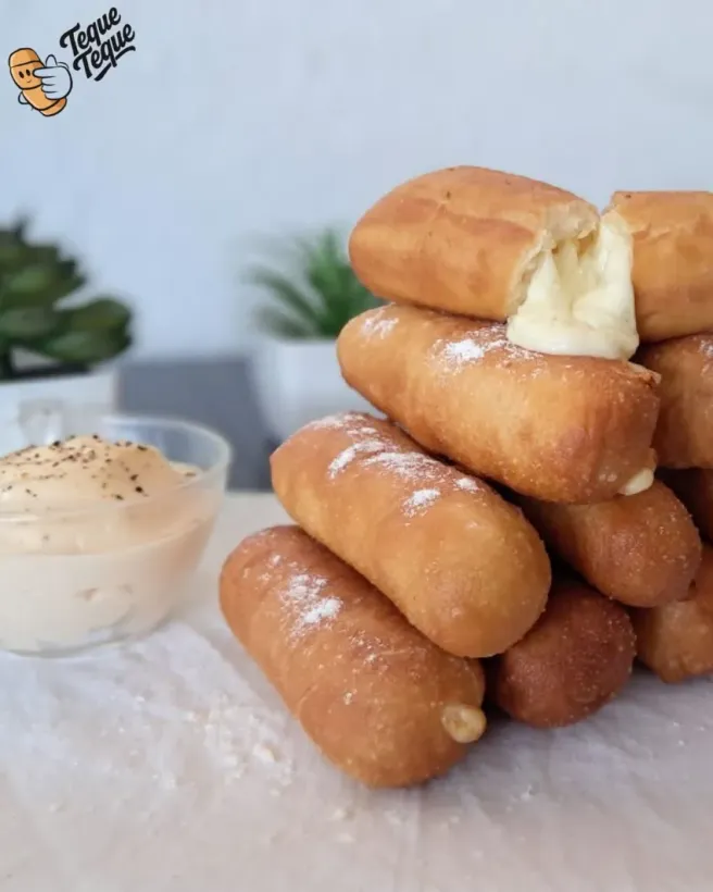 Pila de rollitos fritos dorados con salsa cremosa sobre una mesa.
