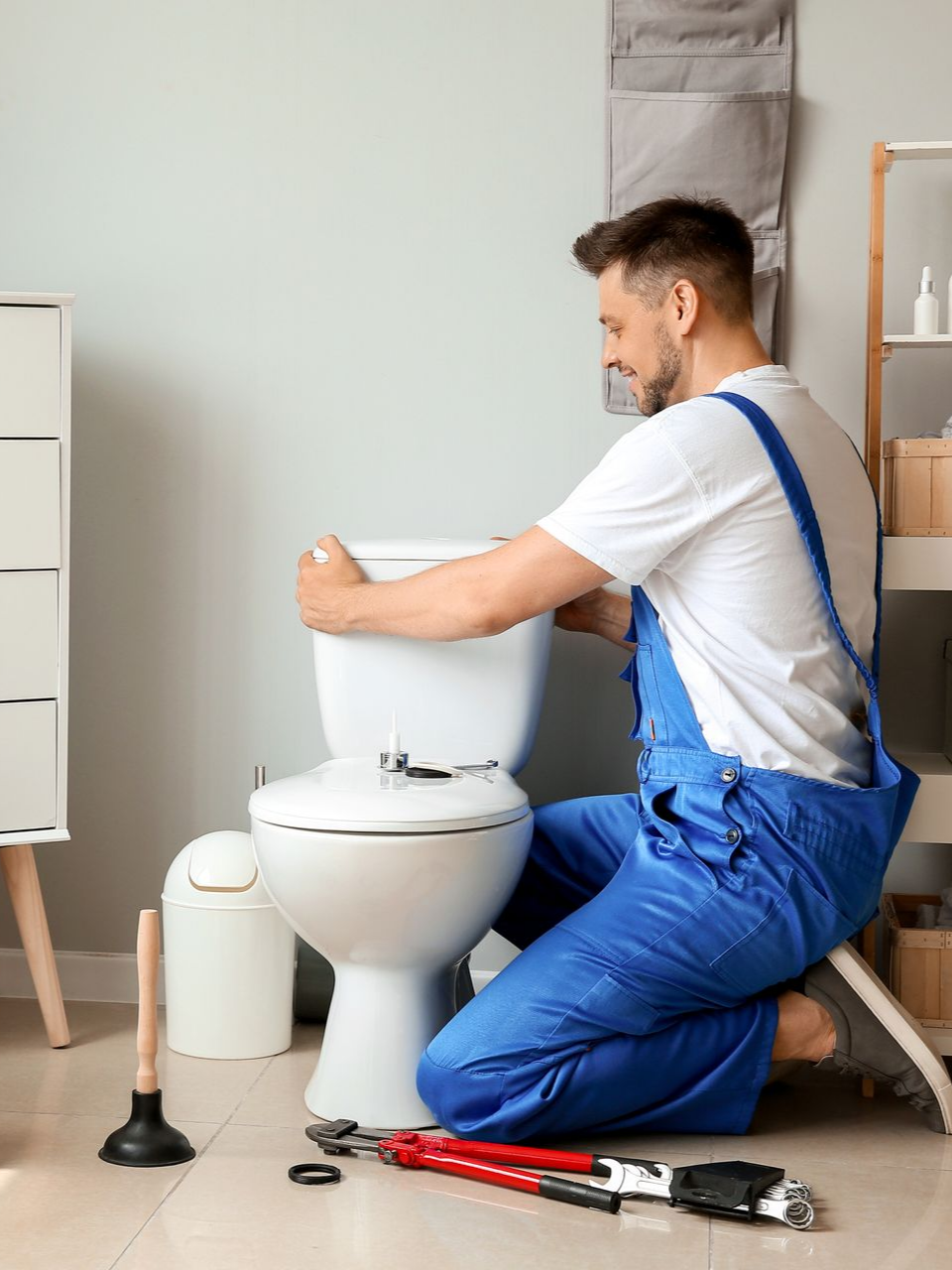Un plombier installe des toilettes dans une salle de bains.