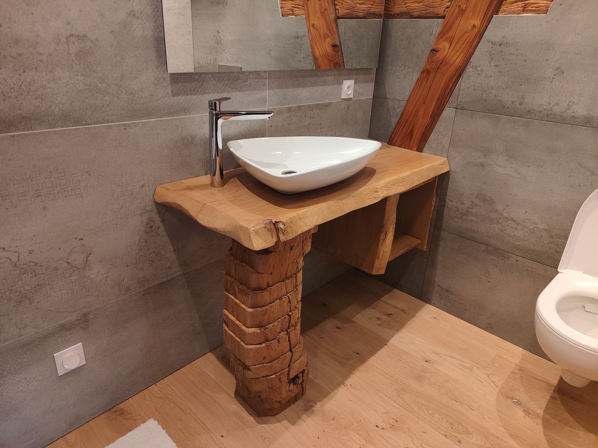 Salle de bains avec un comptoir en bois pour le lavabo, un lavabo blanc et une poutre en bois.