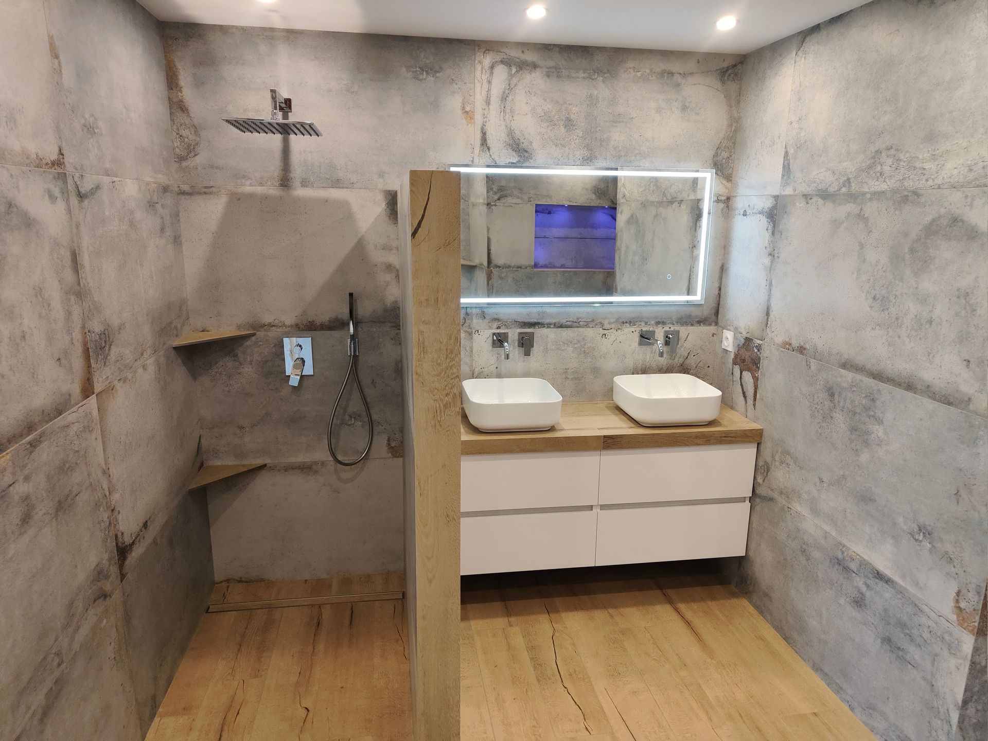 Cabine de douche avec porte en verre, sol clair et robinetterie chromée.