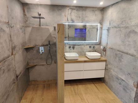 Cabine de douche avec porte en verre, sol clair et robinetterie chromée.