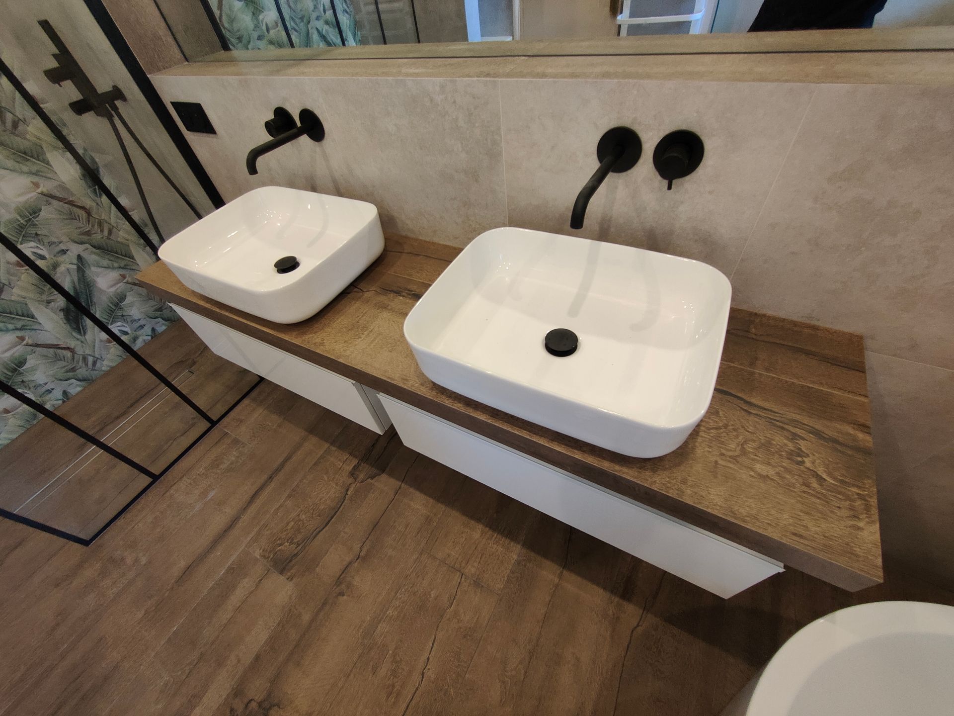 Deux lavabos carrés blancs sur un comptoir en bois dans une salle de bains.