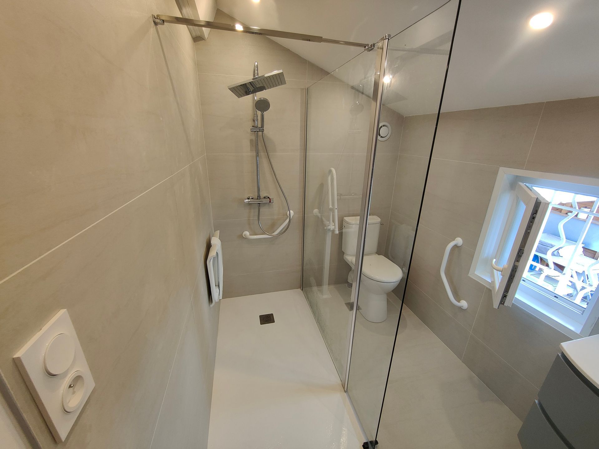 Une main agrippée à une barre d'appui argentée dans une salle de bains.