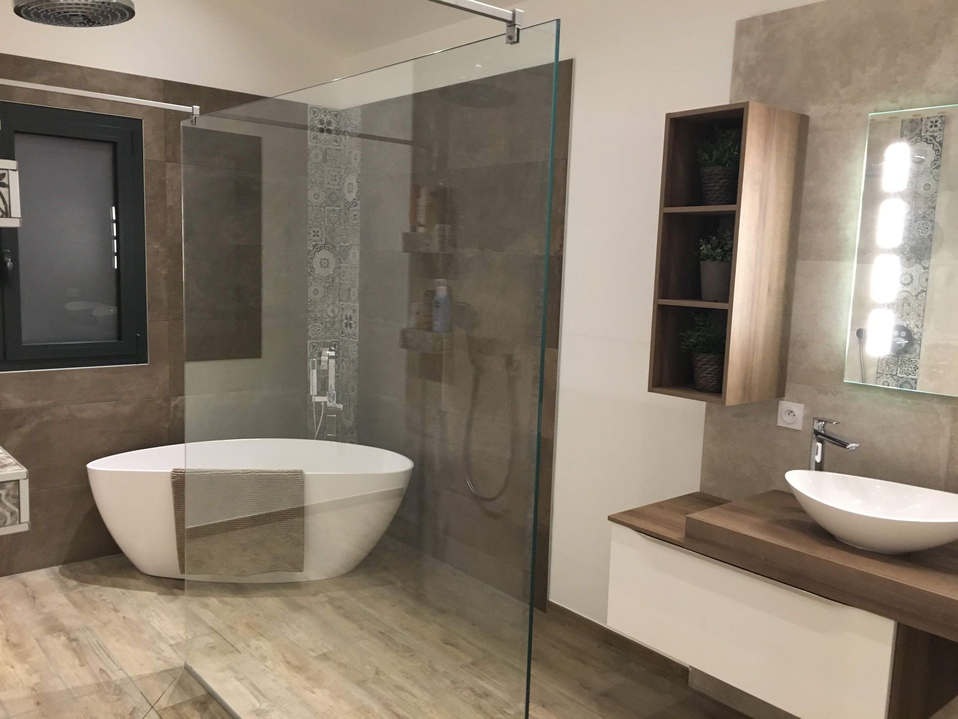 Salle de bains moderne avec douche en verre, baignoire, meuble-lavabo en bois et grand miroir.