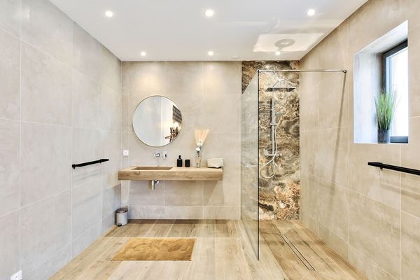 Salle de bains moderne avec douche, baignoire et puits de lumière.