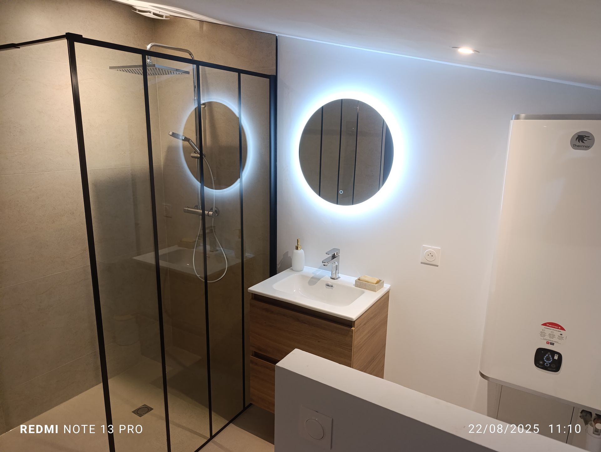 Salle de bains moderne avec douche, meuble-lavabo et chauffe-eau mural.