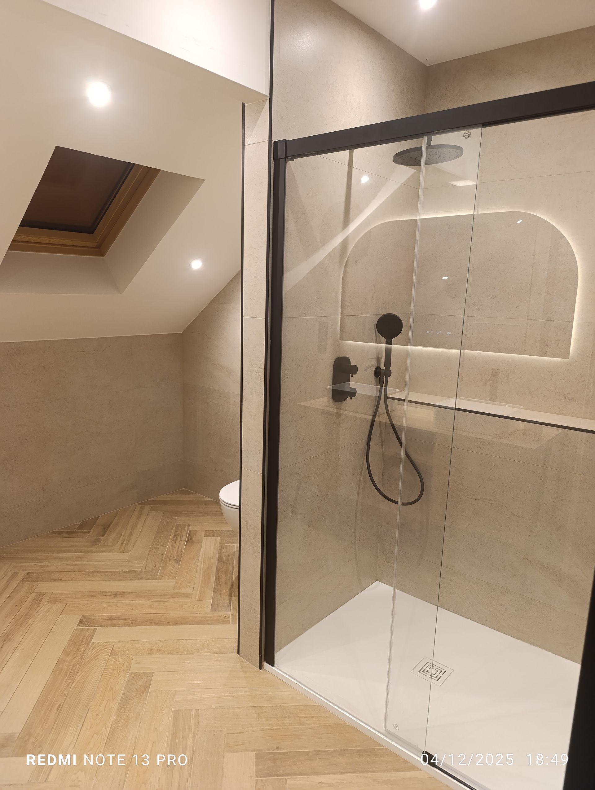 Salle de bains avec murs et sol en marbre blanc, baignoire îlot et douche en verre.